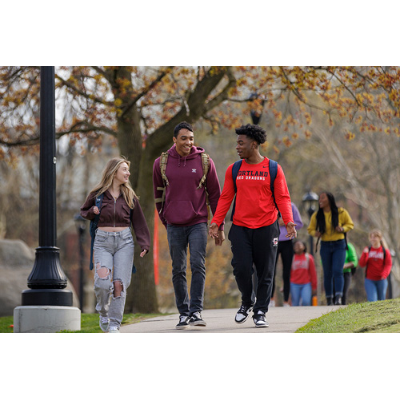 A group of students smiling and walking on the sidewalk