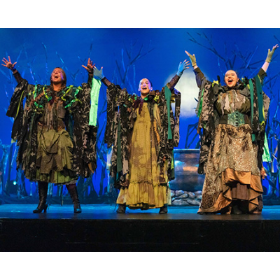 Three witches with arms raised.