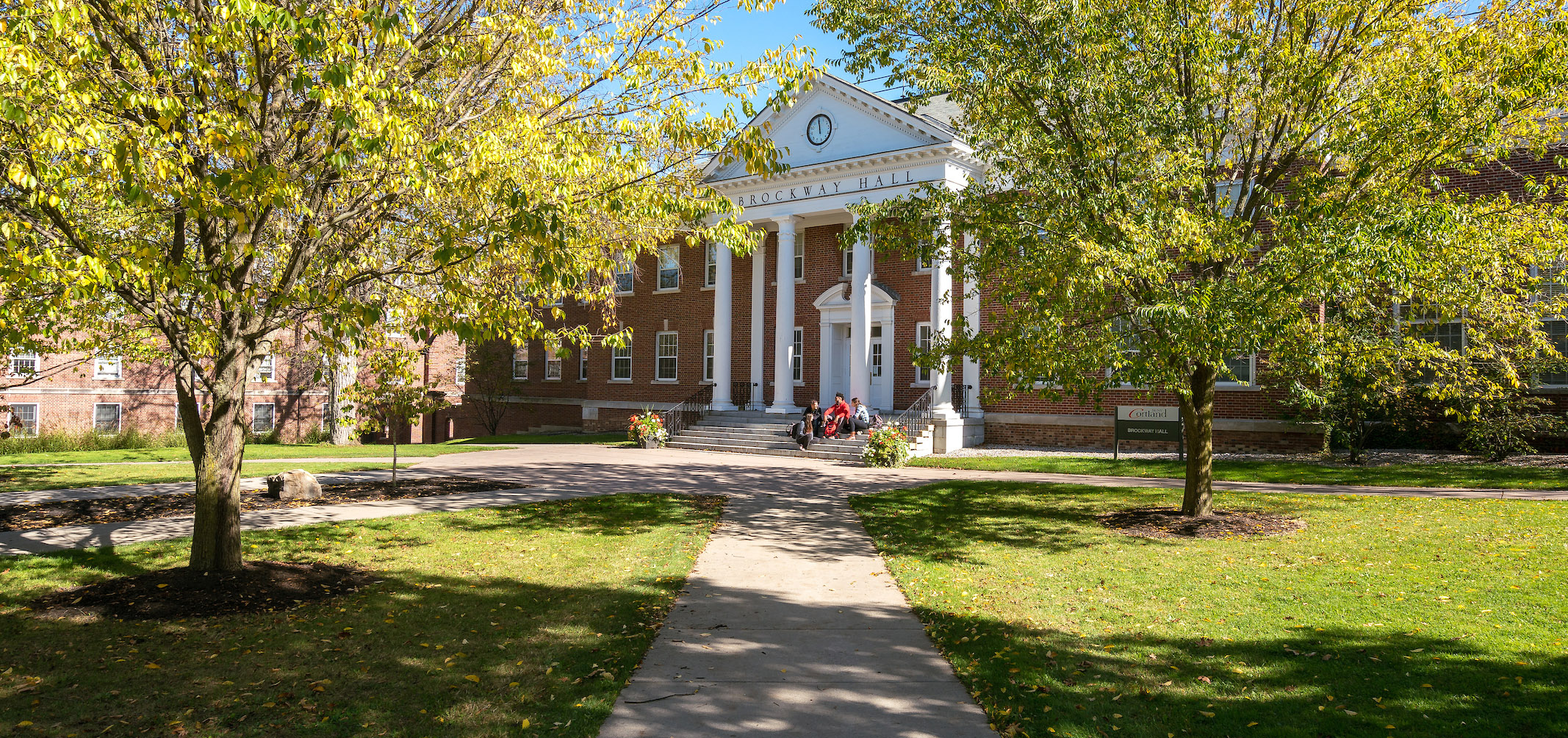 Students sitting on the steps of Brockway Hall on a fall day