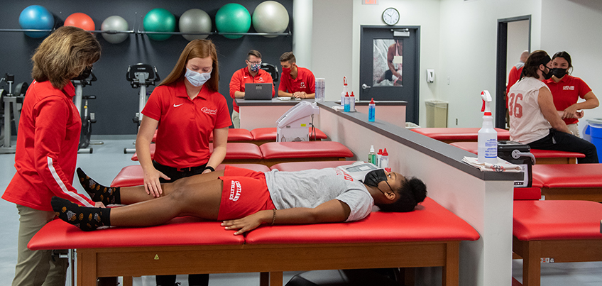 Student getting hands-on athletic training experience with the guidance of a professor