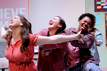 Students smiling on the stage in a scene of "John Proctor is the villain"