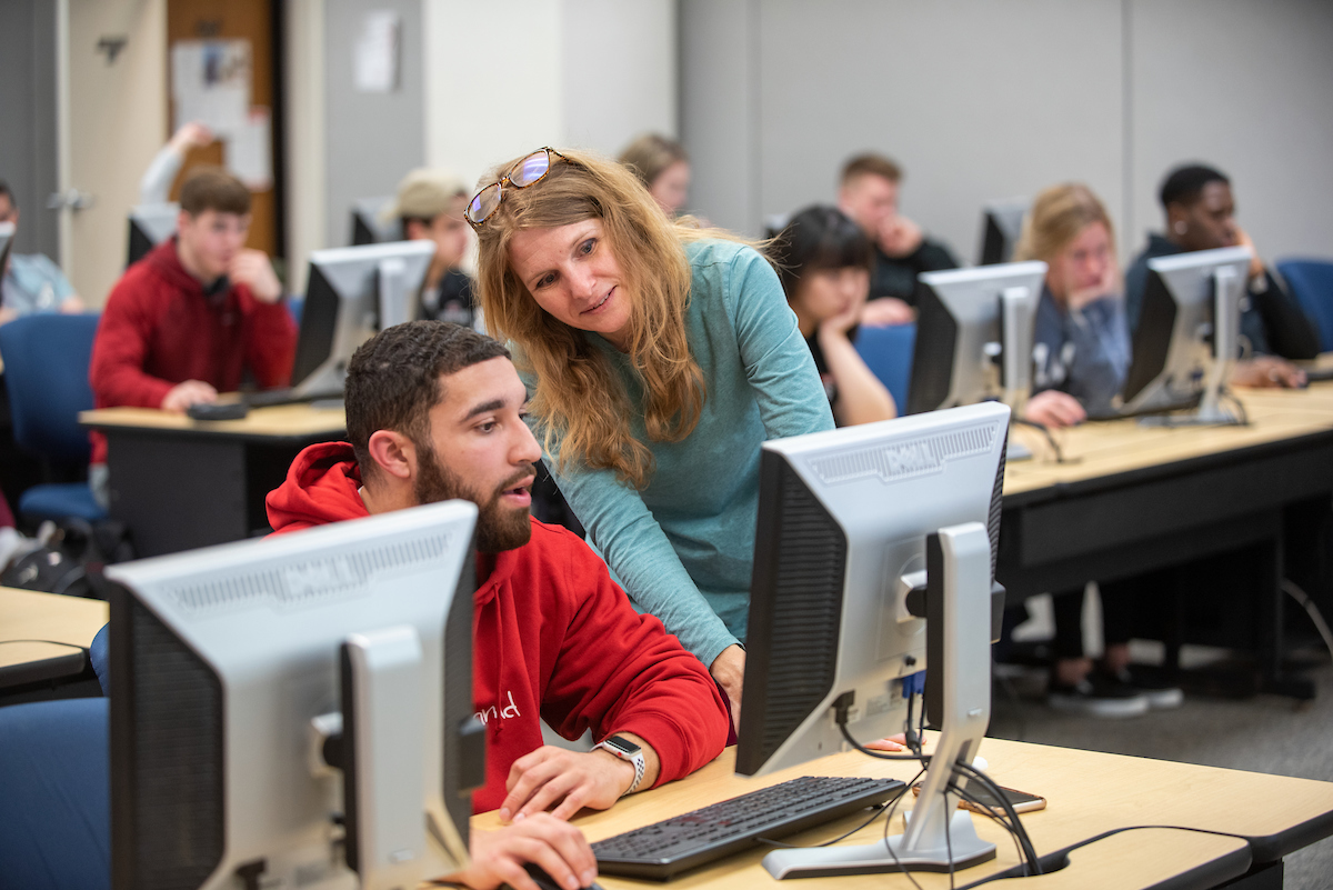 professor assisting student working on a computer
