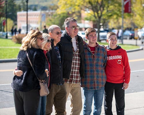 Parents and their students posing for a group photo on campus